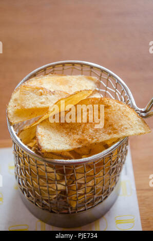 Croustilles de pommes de terre servis dans un panier en acier inoxydable fry. Banque D'Images