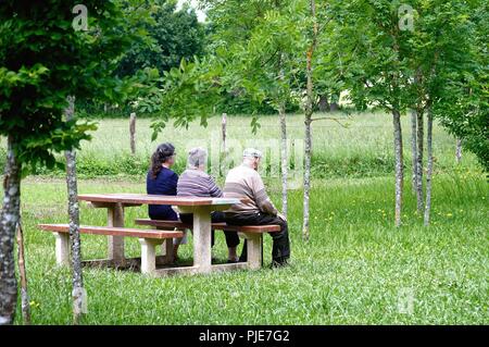 Trois personnes âgées assis sur un banc dans la campagne française près de Mansle, Charente Poitou sud ouest France UE Banque D'Images