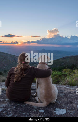 Une femme regardait un soleil africain avec son chien. Banque D'Images