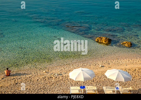 L'homme est assis dans le silence et le calme à l'aube au bord de l'eau de la mer Adriatique au village de Baska, sur l'île croate de Krk Banque D'Images