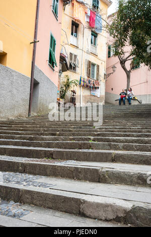 RIOMAGGIORE ITALIE - Le 24 avril 2011 ; Couple de voyageurs s'asseoir sous le té en haut des marches menant à la cuisine italienne traditionnelle et ancienne colline village appartement Banque D'Images