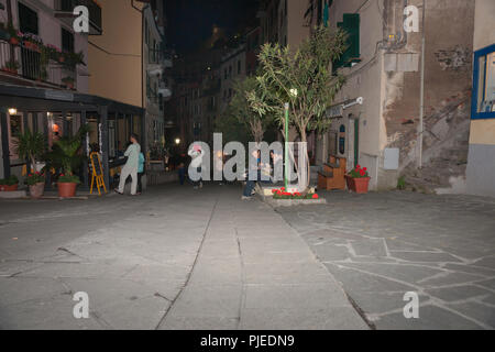 RIOMAGGIORE ITALIE - Le 24 avril 2011 ; les touristes dans la rue du village de nuit restauration et de passer le long de rue menant entre les bâtiments, les restaurants et l'apar Banque D'Images