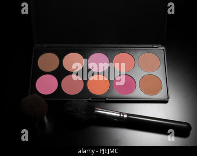 Palette de maquillage Blush contenant avec pinceau sur fond noir. Les produits de l'industrie professionnels de beauté et de l'équipement. Outils d'application de maquillage. Banque D'Images