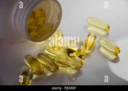 Omega 3 huile de poisson. Capsules spilling out clair d'une vitamine contenant sur une surface blanche.drug store Banque D'Images