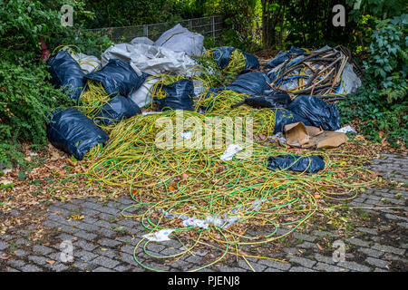 Dépotoir sauvage sur un terrain de stationnement public, l'élimination illégale de déchets de construction, déchets de câbles, à grande échelle, la poubelle a été déposée plus tard f Banque D'Images