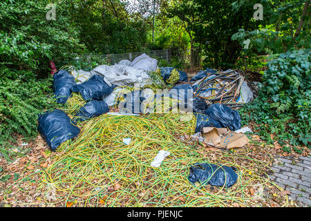 Dépotoir sauvage sur un terrain de stationnement public, l'élimination illégale de déchets de construction, déchets de câbles, à grande échelle, la poubelle a été déposée plus tard f Banque D'Images