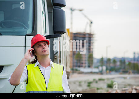 Chauffeur de camion à parler sur son téléphone portable sur un site de construction Banque D'Images