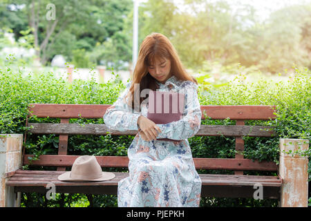 Young Asian woman style rétro en regardant sa montre alors qu'il était assis sur le banc dans le parc Banque D'Images