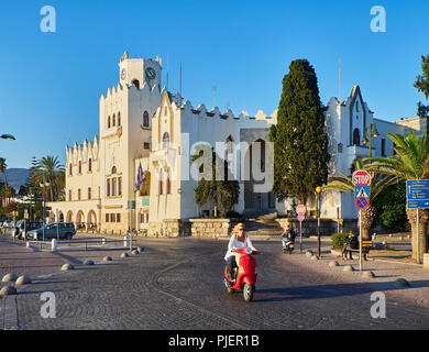 Kos, Grèce - Juillet 3, 2018. Un passage moto Akti Miaouli street avec le Palais du Gouvernement en arrière-plan. L'île grecque de Kos. La Grèce. Banque D'Images