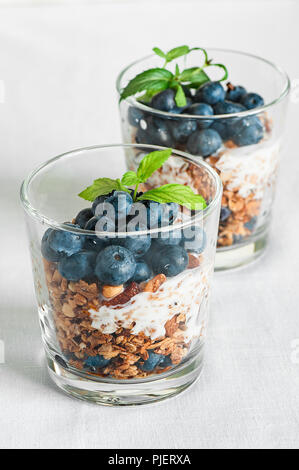 Petit-déjeuner fait maison avec des bleuets et granola yogourt, servi dans les verres sur un fond blanc Banque D'Images