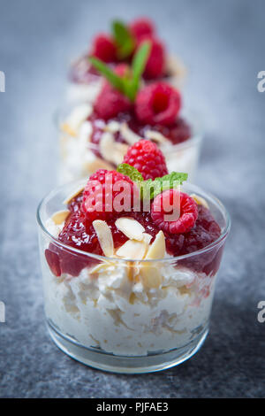 Risalamande est un riz au lait danois froid servi ici dans trois petits contenants en verre dans une rangée sur un fond gris, en dessert avec de la confiture de cerise, Fla. Banque D'Images