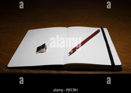 Carnet ouvert sur le bureau d'un artiste. Art Studio objets. Outils de l'illustrateur et designer. Petit livre, un crayon et taille-crayon. Banque D'Images