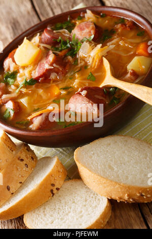 Délicieuse soupe de choucroute avec saucisses et légumes close-up dans un bol sur la table verticale. Banque D'Images