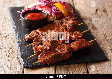 Suya kebab avec sol d'arachides et les épices avec une salade de légumes frais et de ketchup close-up sur la table horizontale. Banque D'Images