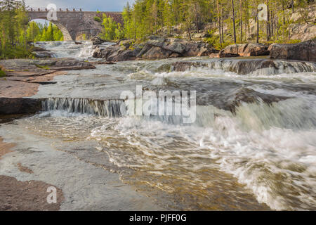 Vieux pont de chemin de fer fait de briques avec un portail, l'eau courante à partir de la rivière sous elle et forêt en arrière-plan, comté de Jokkmokk, en Laponie suédoise, Suède Banque D'Images