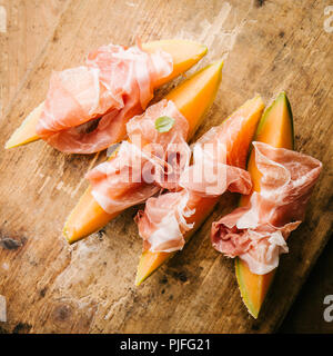 Espagnol savoureux hors-d'méditerranéennes de melon et de jambon sur vintage table en bois. Libre. Image carré Banque D'Images