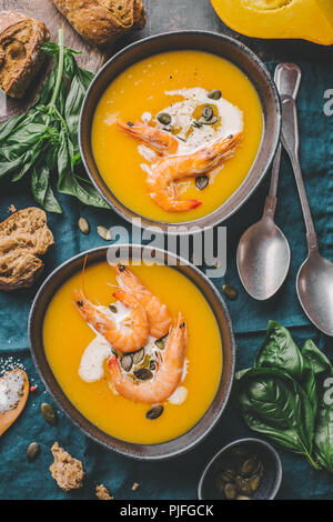 Les aliments d'automne - soupe de potiron à la crème, les crevettes et les graines dans des bols sur la table. Servi pour le dîner. Vue de dessus Banque D'Images