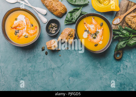 Les aliments d'automne - soupe de potiron à la crème, les crevettes et les graines dans des bols sur la table. Servi pour le dîner. Vue de dessus Banque D'Images