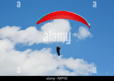 Un vol en parapente dans le ciel bleu du Pays de Galles au milieu des nuages gonflés sur une journée ensoleillée Banque D'Images