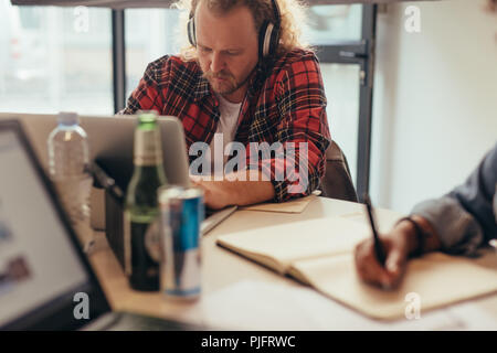 Programmeur mâle working on laptop au démarrage de l'entreprise. Il ingénieur travaillant avec l'ordinateur portable de bureau. Banque D'Images