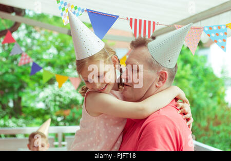 Portrait of happy grandparents celebrating birthday avec leur jolie petite-fille sur la terrasse décorée de couleurs Banque D'Images