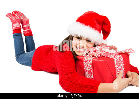 Heureux et cute little Girl with Santa Hat et Red sweater serrant un cadeau de Noël rouge couché sur le sol. Isolated on white Banque D'Images