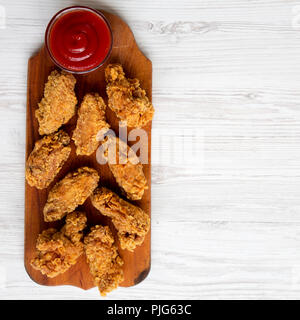 Vue de dessus, des ailes de poulet sur une planche en bois avec la sauce sur la surface en bois blanc. Un espace blanc. Banque D'Images