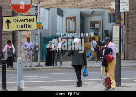 Les Londoniens locales attendent le prochain bus en face d'un panneau publicitaire pour les leviers marketing - un nouvel appartement sur le développement Walworth Road à Elephant and Castle, le 4 septembre 2018, à Southwark, Londres, Angleterre. Les leviers (A) développement de Peabody est un complexe de 1,2,et 3 chambres appartements près de Elephant & Castle et Elephant Park - à la fois l'objet de réaménagement. Banque D'Images