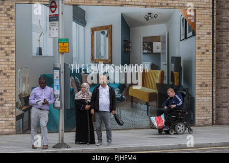 Les Londoniens locales attendent le prochain bus en face d'un panneau publicitaire pour les leviers marketing - un nouvel appartement sur le développement Walworth Road à Elephant and Castle, le 4 septembre 2018, à Southwark, Londres, Angleterre. Les leviers (A) développement de Peabody est un complexe de 1,2,et 3 chambres appartements près de Elephant & Castle et Elephant Park - à la fois l'objet de réaménagement. Banque D'Images