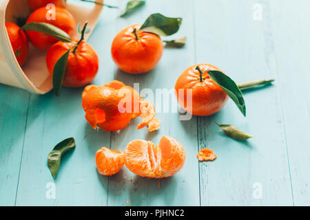 Mandarines mûres avec des feuilles dans un panier sur une table en bois bleu turquoise. Selective focus Banque D'Images