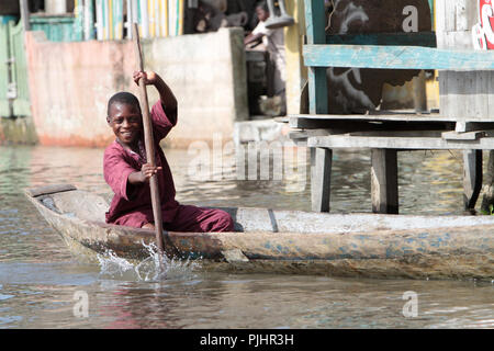 Les enfants béninois pagayer dans un canoë. La ville au bord du lac. Lac Nokoué. Ganvie. Le Bénin. Banque D'Images