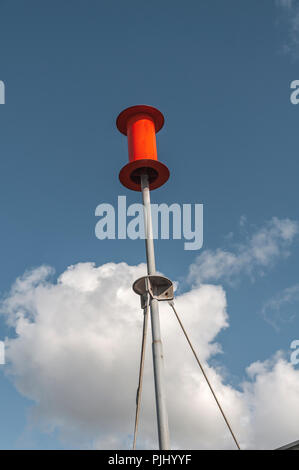 Un poteau en acier attachés à des câbles d'acier avec une orange du tambour en acier fixé sur le haut de la pile Banque D'Images