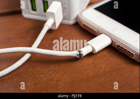 Close up image de câble du chargeur endommagé la connexion avec le smartphone sur la table Banque D'Images