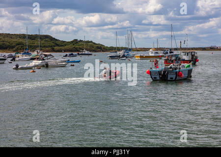 Deux hommes d'un petit canot pneumatique à moteur à travers les amarres à Hengistbury Head, Dorset, UK Banque D'Images