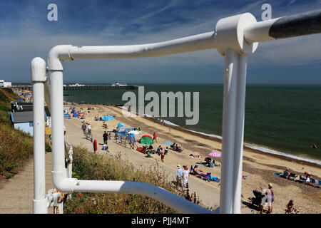 Les gens se détendre devant une ligne de cabines de plage pendant la canicule de 2018 à Southwold, Suffolk, UK. Banque D'Images