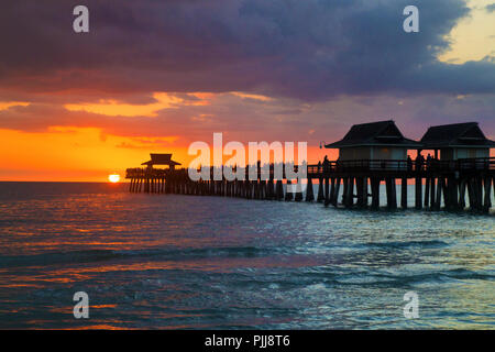 Floride ville de Naples Pier pendant le beau coucher de soleil après une chaude journée ensoleillée, architecture de plage de la jetée au-dessus de la mer Banque D'Images