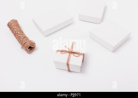 Cadeaux emballage corde de jute. Élégant et minimaliste composition de petit cadeau boîte à côté de la pelote de ficelle et blanc simple présente. Banque D'Images