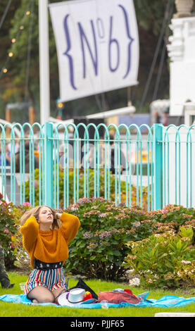 Portmeirion, le Nord du Pays de Galles le 7 septembre 2018 : Festival no 6 est multi-award-winning de la musique, festival des arts et de la culture que tout se déroule dans le magnifique cadre de conte de fées de Portmeirion, au nord du Pays de Galles, l'accueil de l'émission de télévision culte le prisonnier. Un habitué du festival Festival de détente à numéro 6 en jouant avec ses cheveux alors qu'assis sur un tapis de pique-nique, Portmeirion, au Pays de Galles Banque D'Images