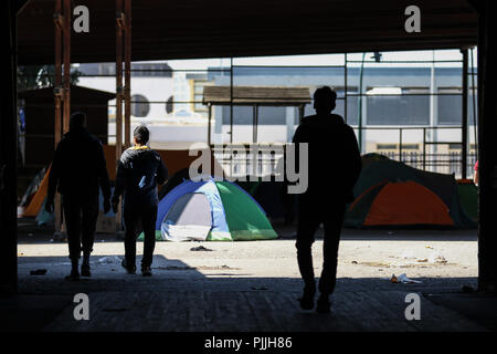 Patra, Achaïe, Grèce. Mar 29, 2018. Silhouettes de réfugiés marche à côté de leurs tentes dans une cour abandonnés.Les Migrants et les réfugiés à trouver refuge dans un camp de fortune qu'ils ont pris à un ancien marchand à côté de port de Patras. Le port de la ville est devenue un important point de départ pour les sans-papiers et les réfugiés qui tentent de se rendre en Italie et de là à d'autres pays en Europe. Essayez les migrants pour accéder au port et se cachent dans les camions en attente d'être envoyé à l'Italie par ferry. Menelaos Crédit : Michalatos SOPA/Images/ZUMA/Alamy Fil Live News Banque D'Images