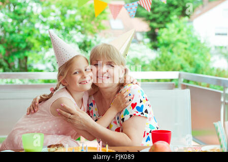 Portrait of happy grandmother hug sa petite-fille à son anniversaire sur terrasse décorée Banque D'Images