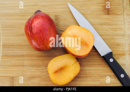 Un plein pluot aux côtés d'un coupés amigo pluot et un couteau Banque D'Images