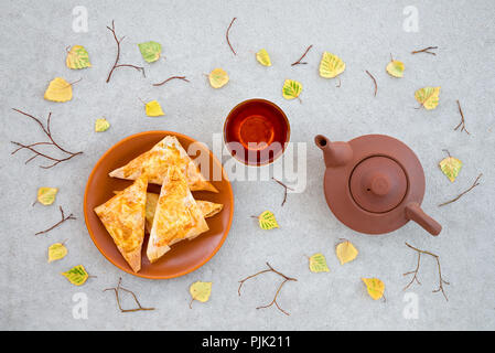 Thé, fromage végétarien tartes et des feuilles d'automne sur fond de béton. Thème de l'automne agréable. Banque D'Images