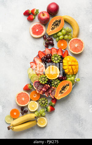 Plateau de fruits - les fruits, mangues, Oranges, fraises, bleuets kiwi Pamplemousse Raisins, bananes pommes sur la plaque blanche, sur l'off white tabl Banque D'Images