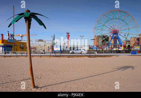 Plage avec palmier artificiel dans Coney Island, Brooklyn, New York City, USA, dans l'arrière-plan le Luna Park avec grande roue, Banque D'Images