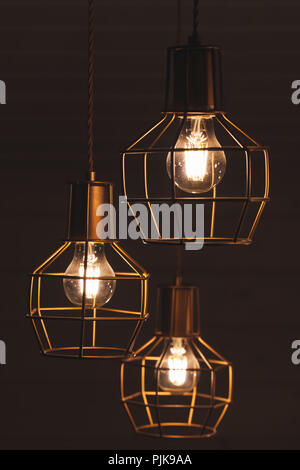 Lustre suspendu au plafond avec trois lampes ampoule LED jaune, éléments d'éclairage recouverts de métal wire frame d'abat-jour, photo verticale avec Banque D'Images