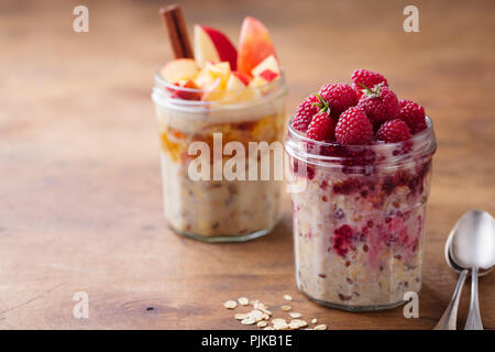 Du jour au lendemain de l'avoine, Bircher muesli avec pommes et cannelle, framboise dans des bocaux en verre sur fond de bois Banque D'Images