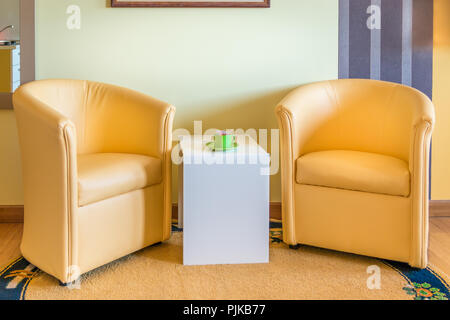Deux fauteuils en cuir jaune et blanc table basse dans le salon salon de l'appartement. Chambre lits jumeaux hôtel moderne de l'intérieur. Banque D'Images