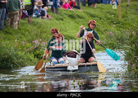 Les gens en costumes de chien un radeau d'aviron le long d'une rivière à la Plaine des jeux, Thorney, Somerset, Angleterre Banque D'Images