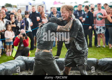 Deux hommes aux prises avec une foule de boue derrière à la Plaine des jeux, Thorney, Somerset, Angleterre Banque D'Images