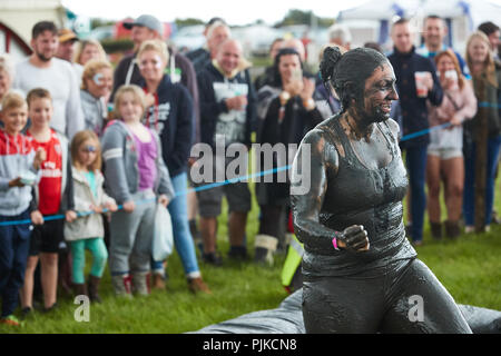 Femme debout couvert de boue à un concours à la lutte de boue Jeux de plaine, Thorney, Somerset, Angleterre Banque D'Images